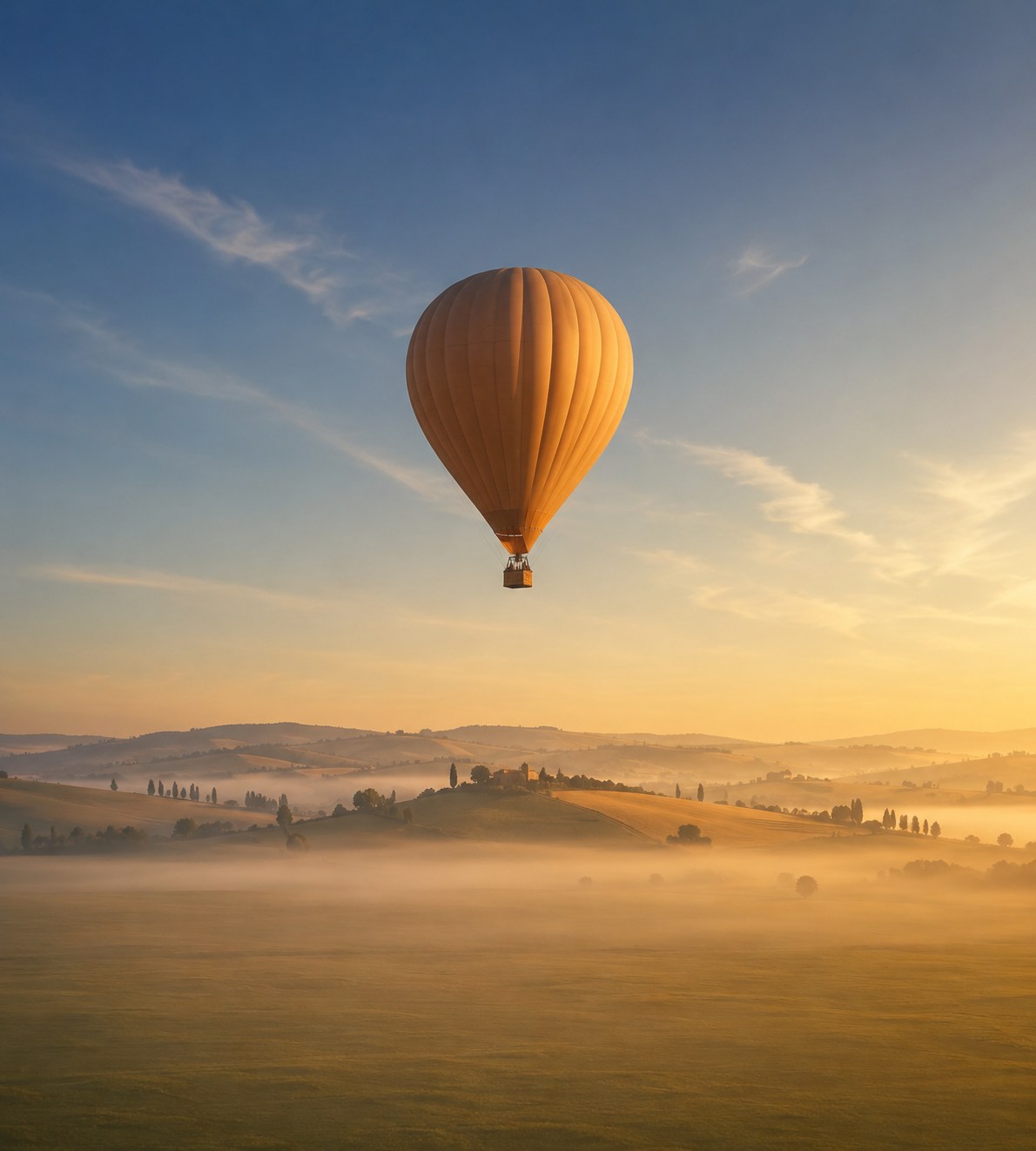 Montgolfière au-dessus de la campagne au coucher du soleil